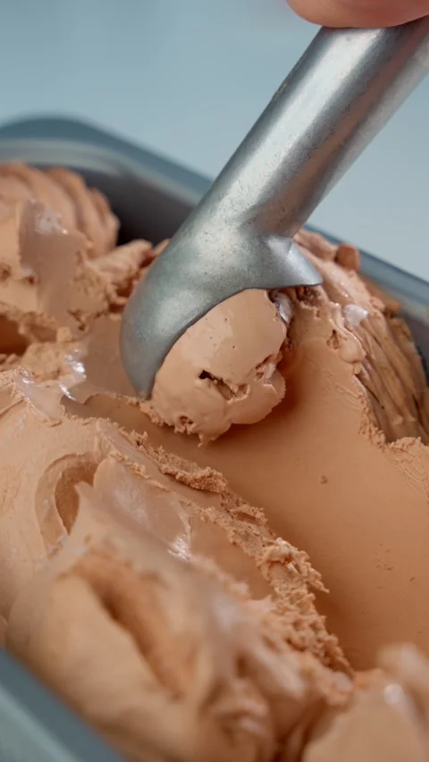 Use spoon to form ball of chocolate ice cream in container. Concept of summer Stock Footage 275742812