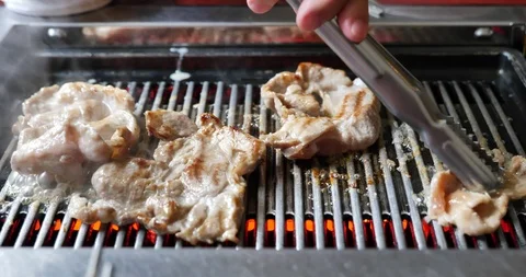 Use tong pinch Korean BBQ grilled pork meats on Electric Grill Griddle. Stock Footage 113762553