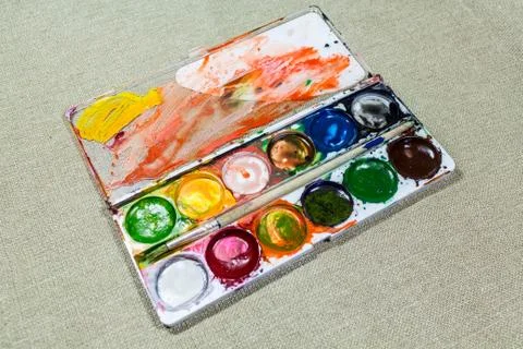 Used box with multi-colored paints on a fabric background. Diagonally 스톡 사진