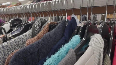 Used clothing store rack showcasing various sweaters and garments in sequence Vídeos de archivo 343453723