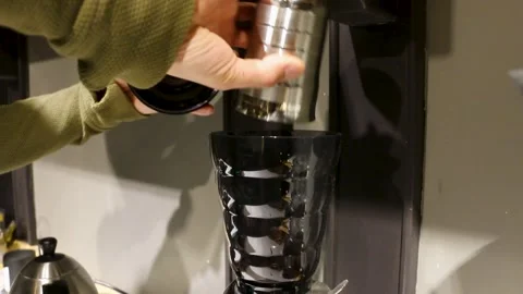 Used coffee grounds drop from a stainless dosing cup. They fall into a black Video stock 309646074