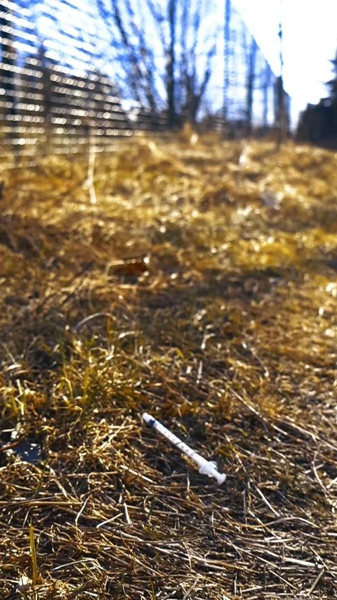 Used Discarded Syringe Lying on the Grass, Bokeh Background Stock Footage 333101944