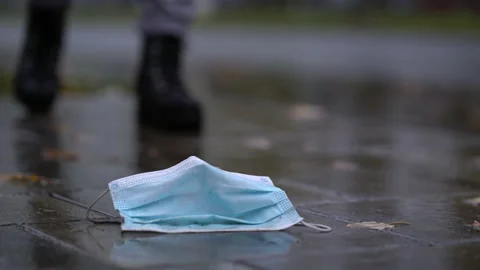 Used disposable face mask in puddle during rain Stock Footage 141859035