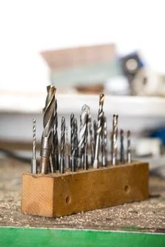 Used drills on a table in workshop, shallow focus Stock Photos