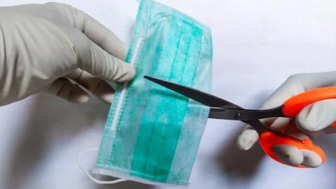 Used Face mask disposal by cutting it using scissors. Stock Photos