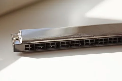 A used harmonica is located in the window frame Stock Photos