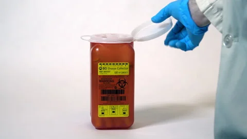 Used hypodermic needle is disposed of in small sharps container. Stock Footage 306828385
