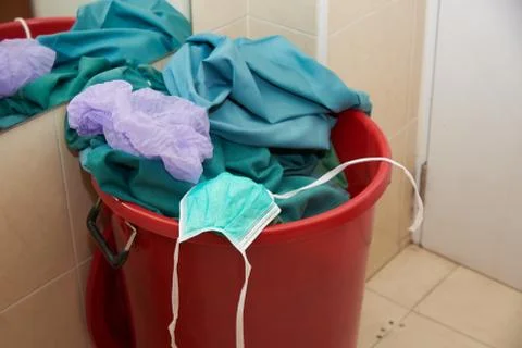 Used mask, cap and clothes in garbage bin Stock Photos