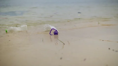 Used plastic bottle washed onto a sandy shoreline by ocean waves Stock Footage 344604413
