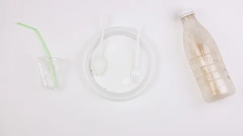 Used plastic disposable tableware garbage moves on white, non eco party Stockbeeldmateriaal 113204551