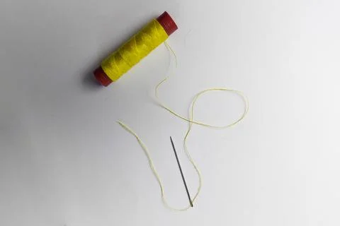 Used yellow thread and needle on a white background Foto stock