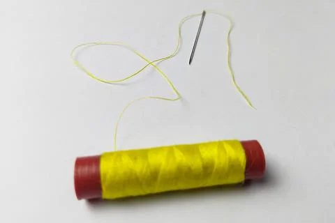 Used yellow thread and needle on a white background Foto stock