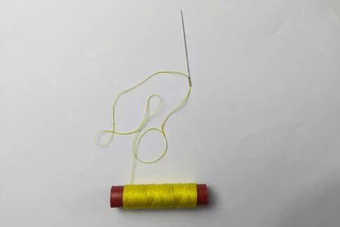 Used yellow thread and needle on a white background Foto stock
