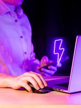 User at computer with glowing lightning symbol on mobile 库存照片
