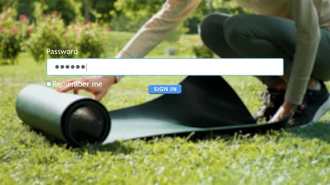 User enters password on website while a woman prepares sports mat outdoors Stock Footage 334022399