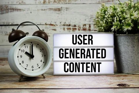 User Generated Content text on light box with alarm clock on wooden backgroun Stock Photos