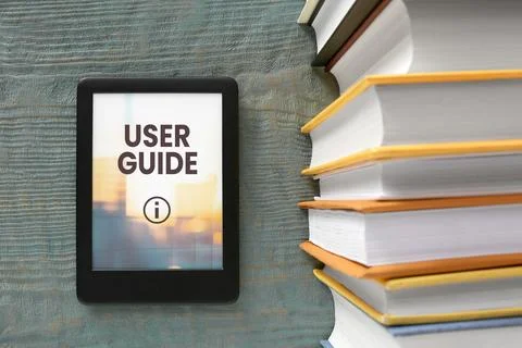 User Guide document open in e-book device and different book on wooden tabl.. Stock Photos