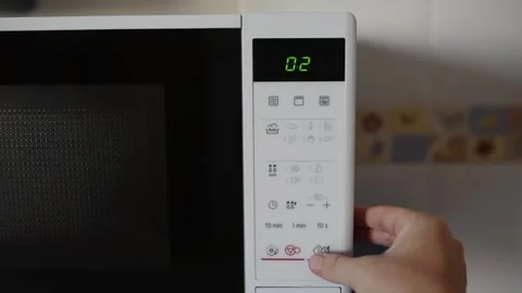 User hand selects defrost mode and sets time on digital display of microwave. Stock Footage 337469873