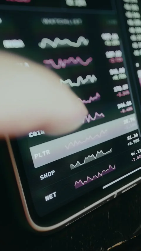 User interacting with a mobile stock trading application with real-time data for Stockbeeldmateriaal 333862723