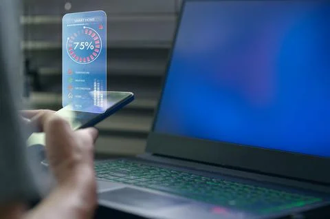 User Interacting with Smart Home Interface on Smartphone and Laptop Stock Photos