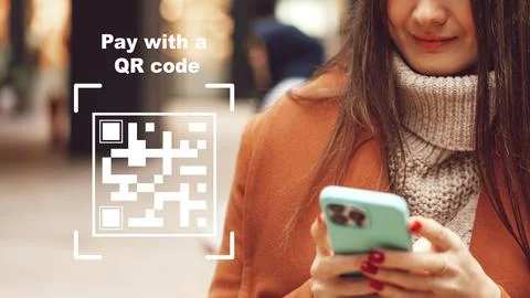 User makes an online payment using a QR code while holding a smartphone in a Stock Photos