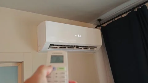 User operates home air conditioner with remote control in living room Stock Footage 340549647