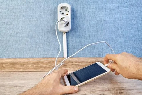 User is plugging mobile phone into charge. Stock Photos