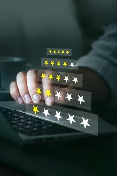 User provides feedback rating using star graphics on a laptop while sitting at Stock Photos