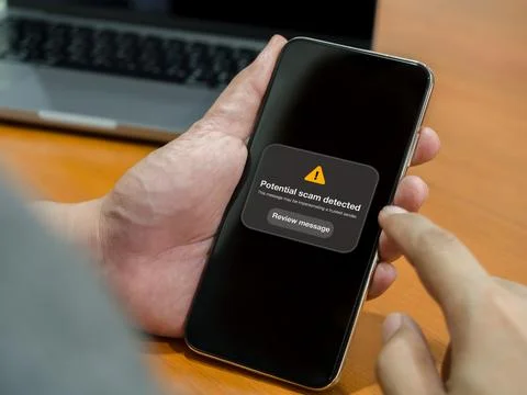 User receives a potential scam warning on smartphone screen before taking a.. Stock Photos