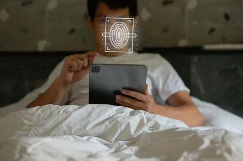 User Unlocking Device with Fingerprint Scan While in Bed Foto stock