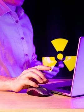 User working on computer with yellow hazard symbol on phone 库存照片