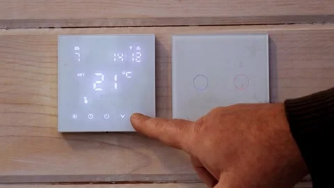 Users hands adjusting thermostat to setting it to 22C. Adjusting wall thermostat Stock Footage 326967580