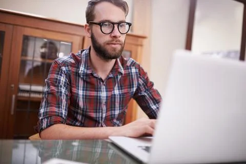 Using all the latest tech. Shot of a handsome young hipster working on a laptop. Foto stock