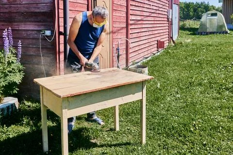 Using angle grinder for sanding tabletop, craftsman wearing respirator and .. Foto stock