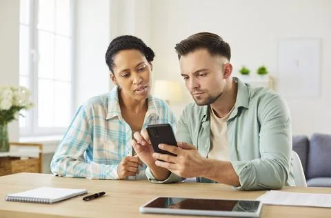 Using app on smartphone while managing family finances at home together Stock Photos