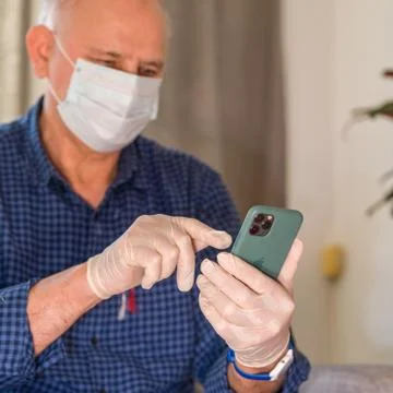 Using Apple iPhone 11 Pro smartphone during Coronavirus with Mask and gloves Foto stock