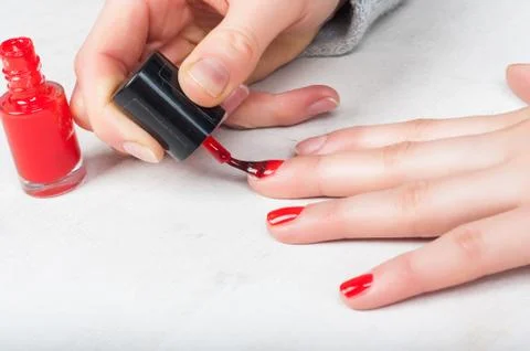 Using applicator brush to apply red polish to fingernail, self made manicur.. Stock Photos