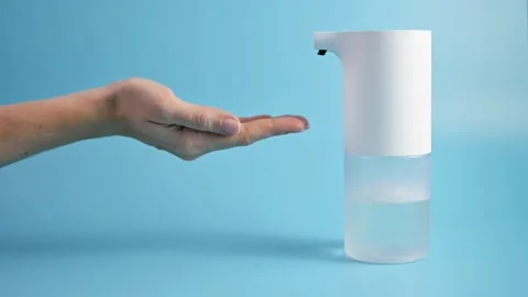 Using automatic soap dispenser. Young girl woman brings her hands to dispenser Видео 170047840