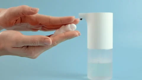 Using an automatic soap dispenser. Young girl woman brings her hands to Видео 221253649