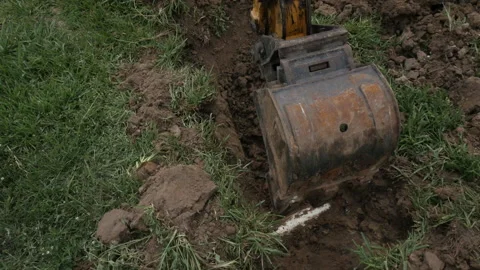 Using a backhoe to dig up a sewer pipe for repairs in a backyard Stock Footage 198421956