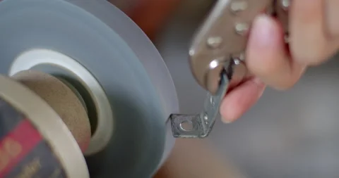 Using a bench grinder to shape or polish metal components with sparks flying. Stock Footage 312311981
