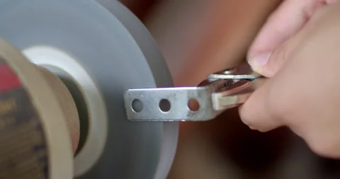 Using a bench grinder to shape or polish metal components with sparks flying. Stock Footage 312311998