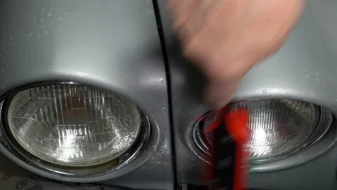 Using a brush and soapy water to clean the paintwork and headlamps of an old car Video stock 221242377