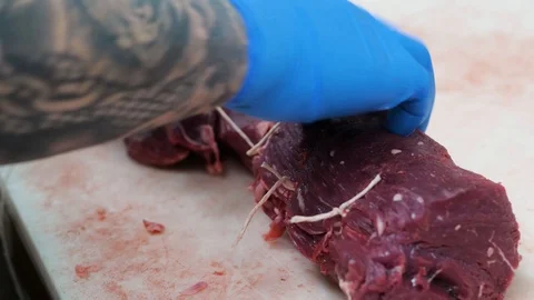 Using butchers strings for tying uncooked fresh meat close up shot Stock-Footage 104973438