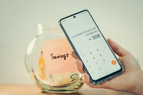 Using calculator on smartphone to count savings Stock Photos