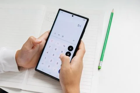 Using a calculator on a smartphone for homework and math exercises. Mobile te Stock Photos