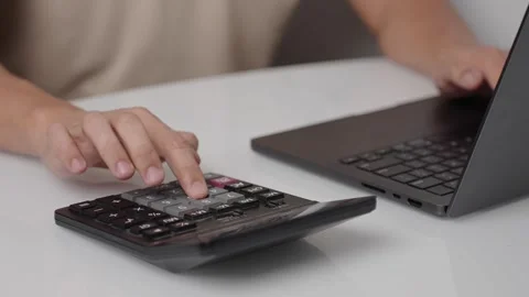 Using a calculator while typing on a laptop for quick calculations Stock Footage 321147867