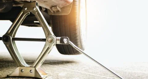 Using a car jack to lift a car to change a spare wheel with copy space Stock Photos