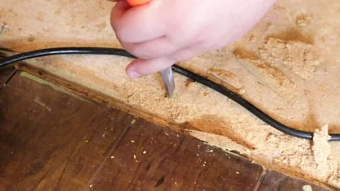 Using a chisel and hammer to pry out old nails from subflooring Stock Footage 150600152