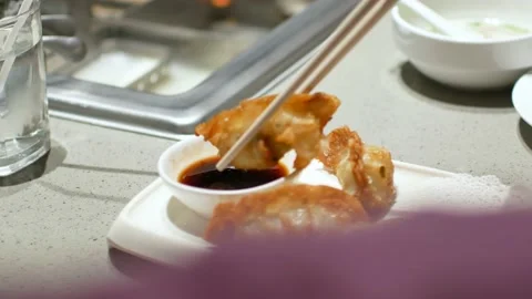 Using chopstick pick up  gyoza - fried wonton from the plate dipping into sau Stock Footage 206763775